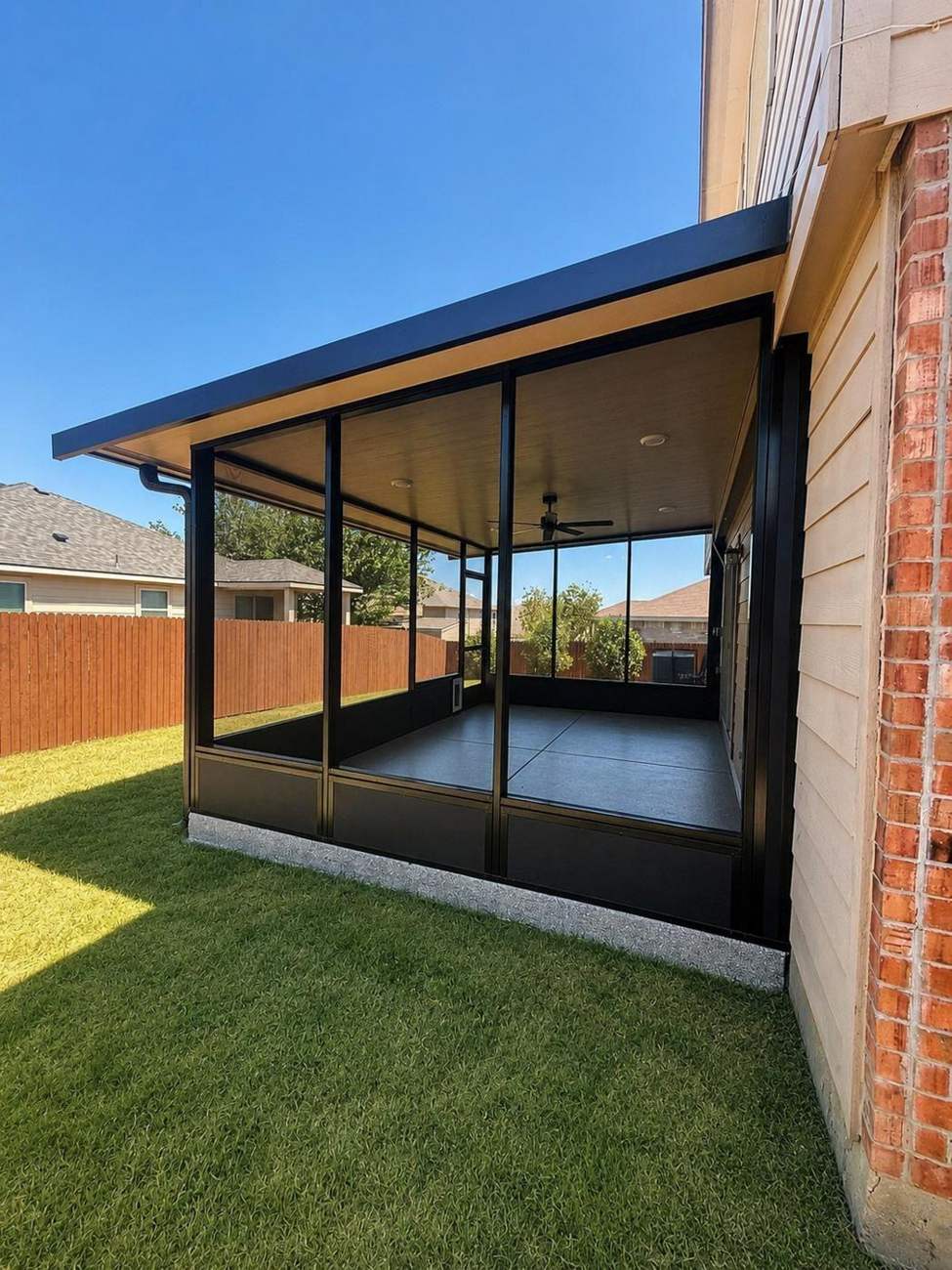 Cantilevered flat cover with screen room, black frames against brick
