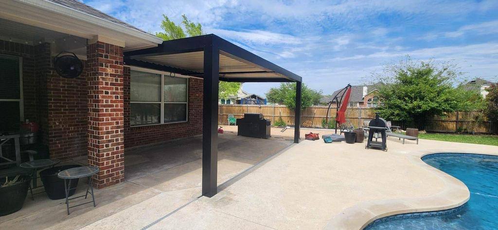 Freestanding black flat-roof cover between the brick home and the pool